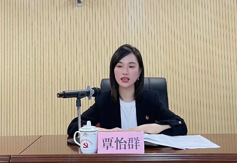 覃怡群坐在会议桌前参加公开活动