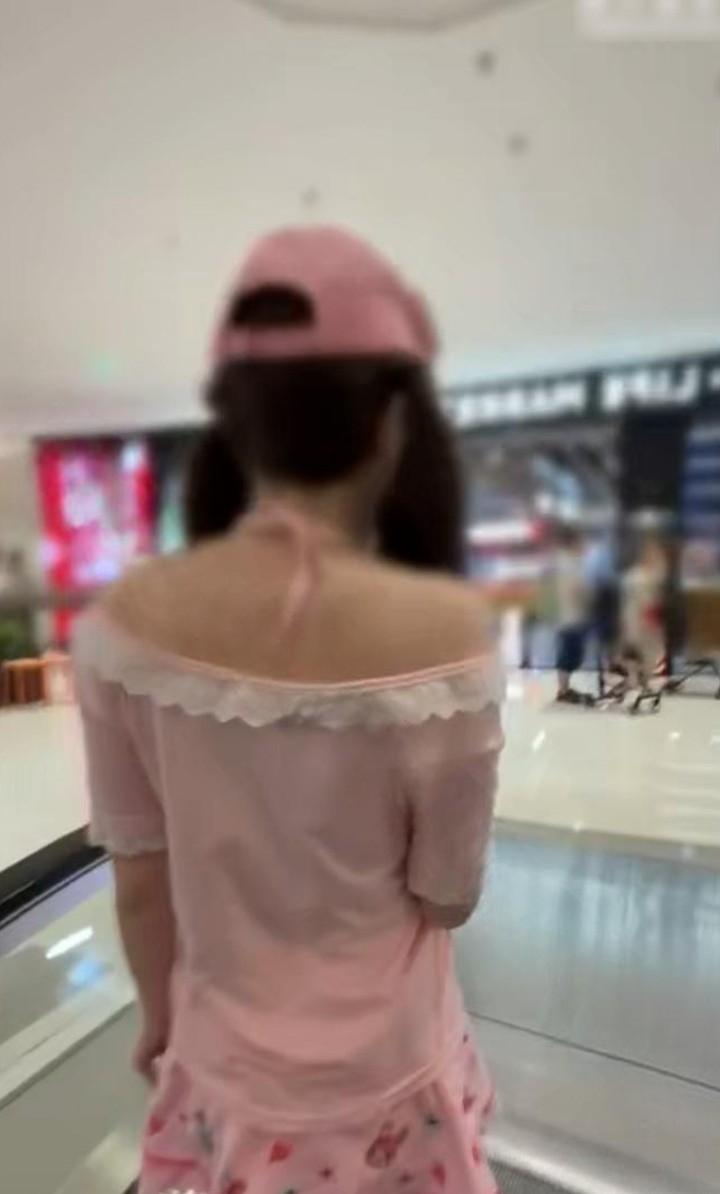 粉色穿搭女子乘坐商场扶梯