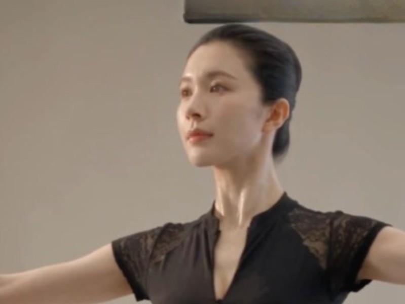 身穿深色舞衣的角色在室内展开双臂
