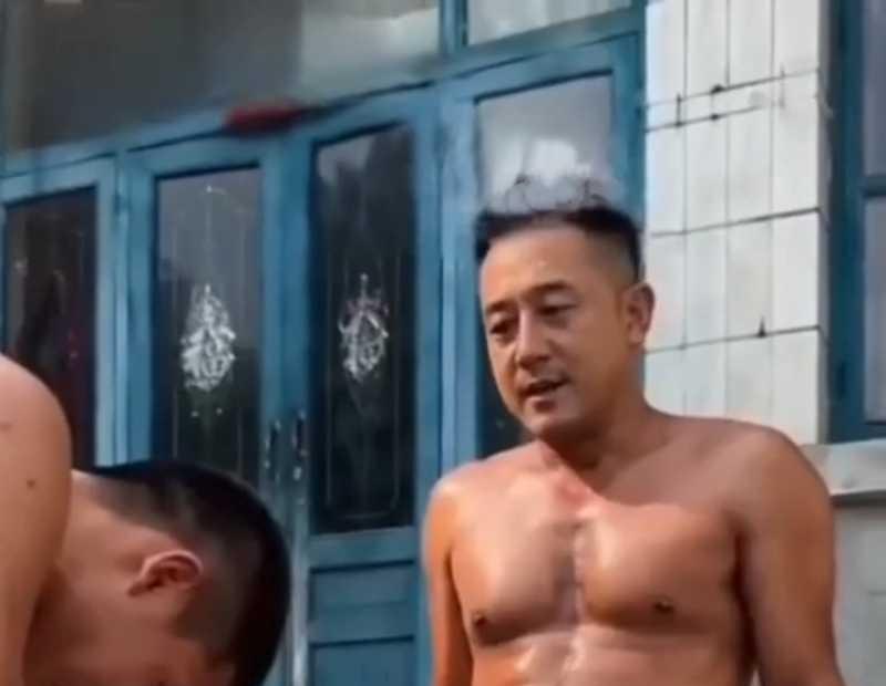 男子坐在农家院蓝色门前台阶