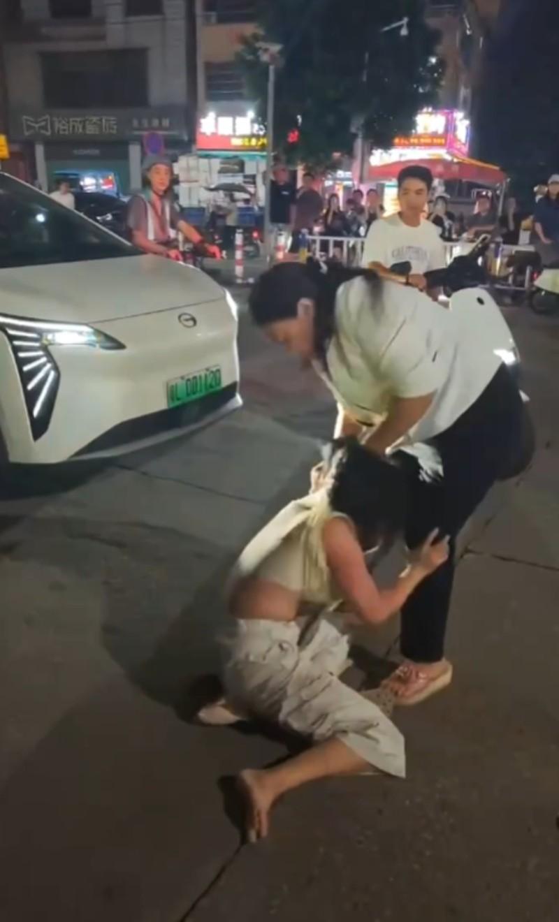 女子冲突发生在停放车辆旁的街道路面