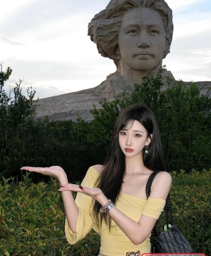 彩儿穿黄色上衣站在户外雕像前