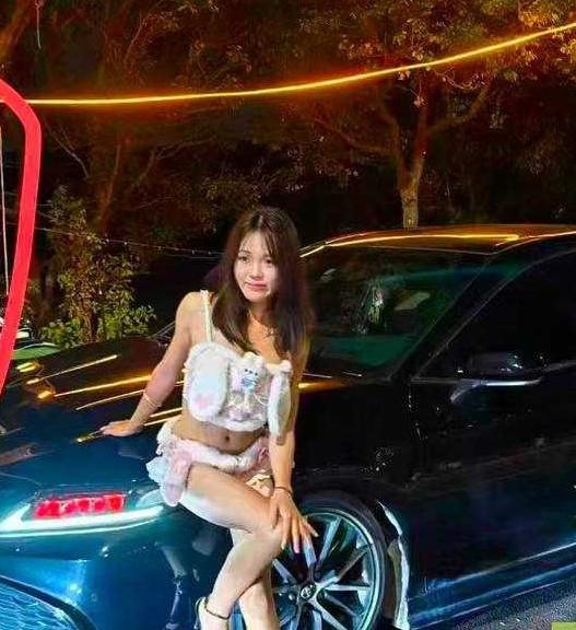 白裙女子坐在蓝色轿车车头旁