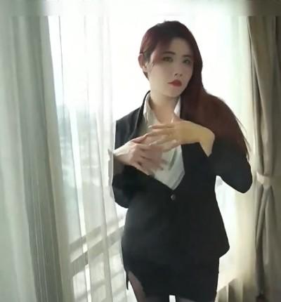 费爵娜身穿黑色西装站在落地窗前